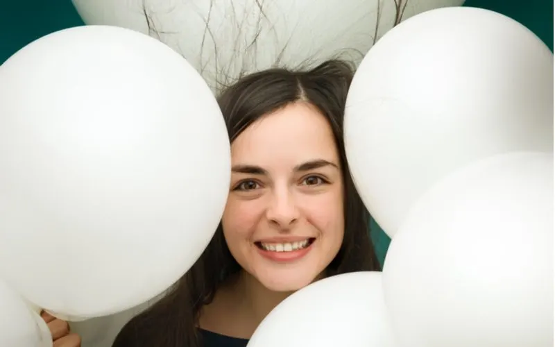 Woman smiling in the middle of a bunch of balloons for a piece on how to get rid of static hair