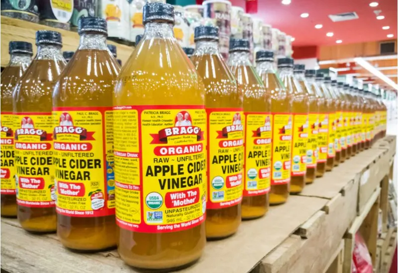 Many bottles of apple cider vinegar sit in large rows on a pallet