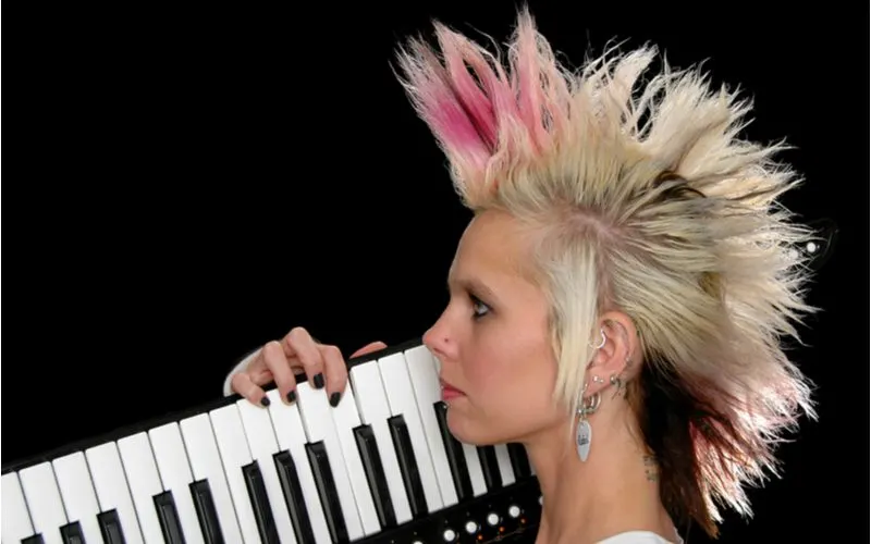 Crazy woman with punk hair in a spikey mohawk holding a portable keyboard to her face