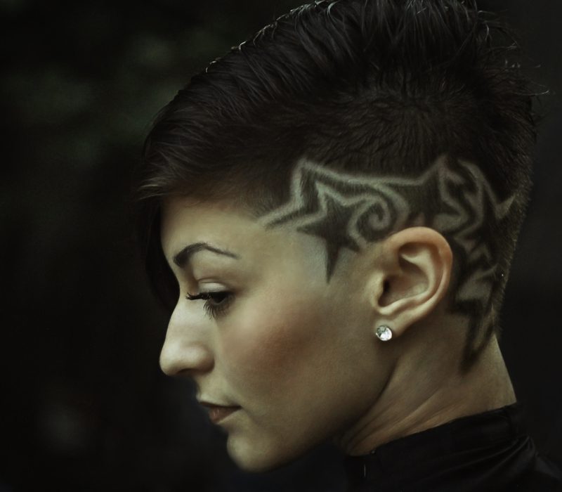 Woman rocking a low fade haircut with a star and pattern shaved into the left side in a side profile image