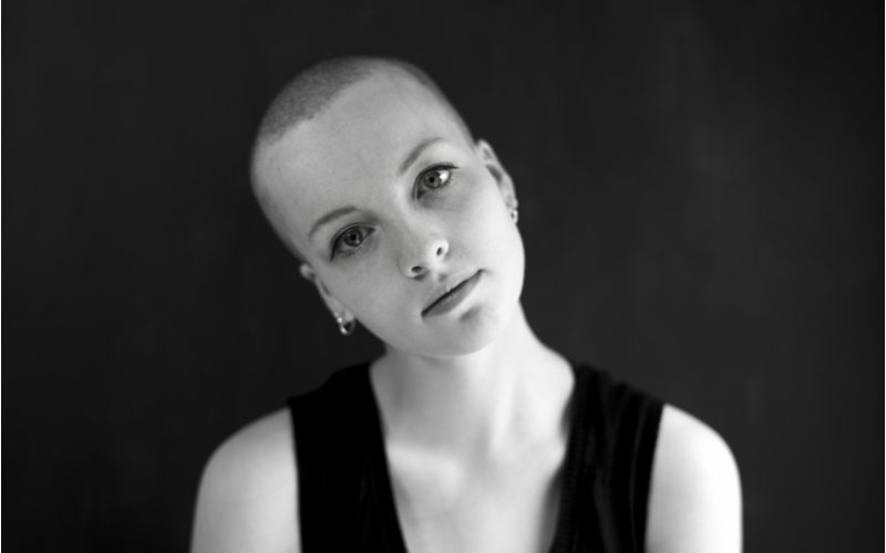 Woman wearing a buzzcut hairstyle in a black and white image tilting her head to the right