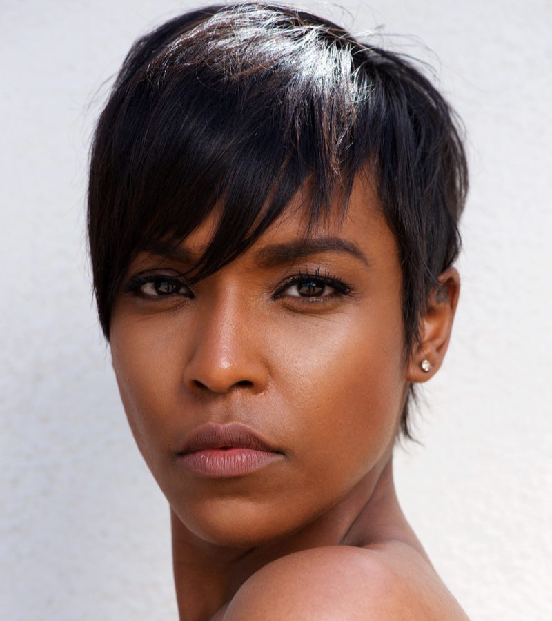 Black woman with a pixie cut looking to her left while wearing a white shirt