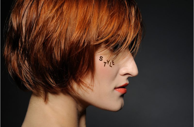 Woman with a traditional shag haircut with red hair and fair skin in a dark room