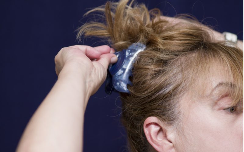 Woman clipping her hair into sections above her head for a piece on what is a hair diffuser