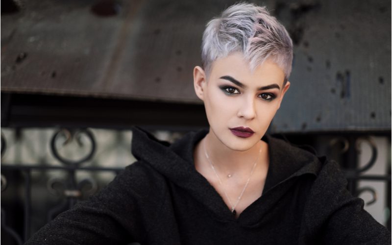 Pixie Perfect punk hairstyle on a woman in a black sweater standing in front of a metal bridge