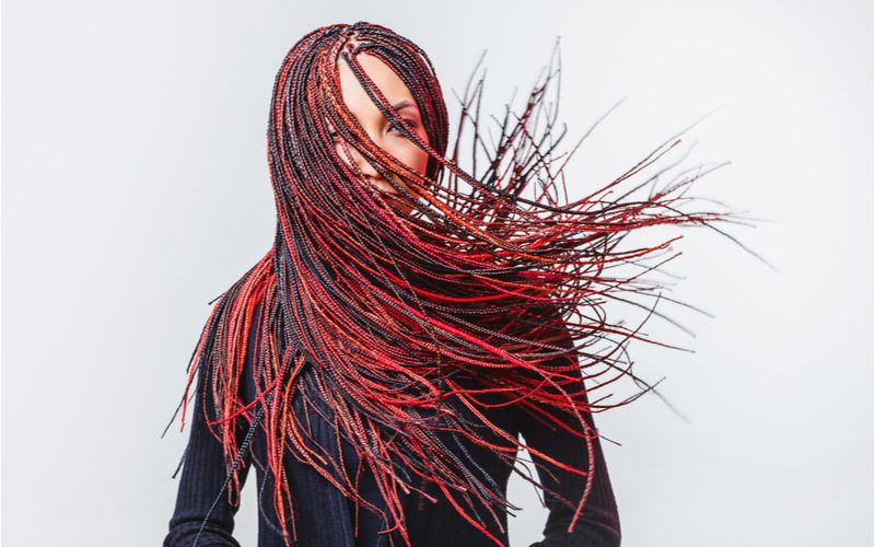 Image of a woman in a studio with two tone hair in red and black box braids