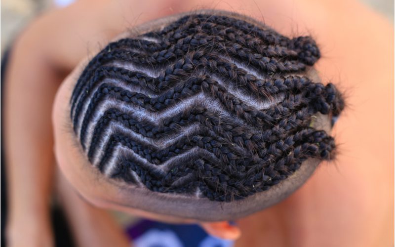 Man with zigzag braids on the top of his head that turn into small buns at the back shown from an aerial image