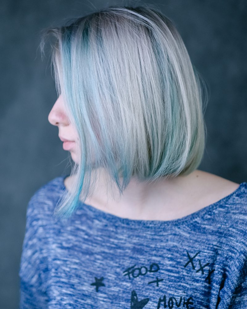 Choppy long blonde bob haircut with lowlights on a woman in a fancy blue shirt