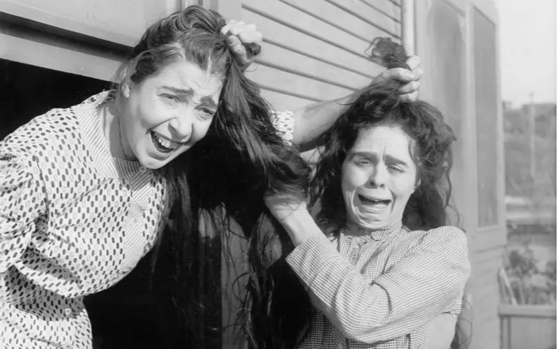 Black and white photo of two women pulling each other's hair for a piece on what is hair cracking