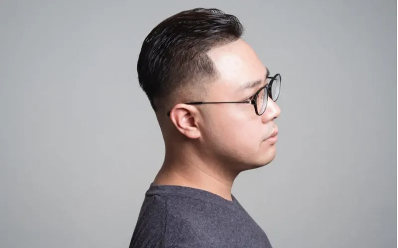 Side profile of a man with a Pompadour Low Skin Fade haircut wearing glasses in a studio