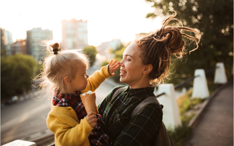 For a piece about dreadlocks, a woman with this style holds a baby while her hair is tied up above her head
