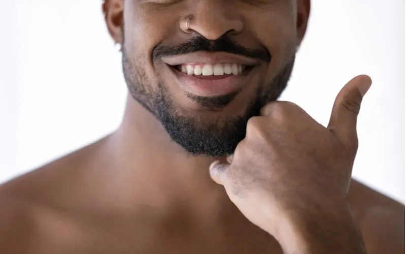 Short Balbo Beard on a handsome black man without a shirt holding his left fist to his chin