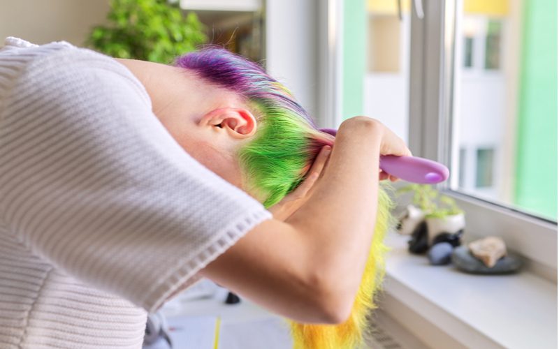 Mardi Gras Underdye hair inspiration on a woman with her head down brushing the top of her hair