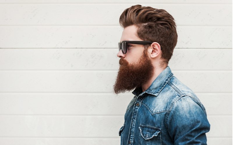 Full ducktail beard style on a guy in a jean jacket in a side profile image
