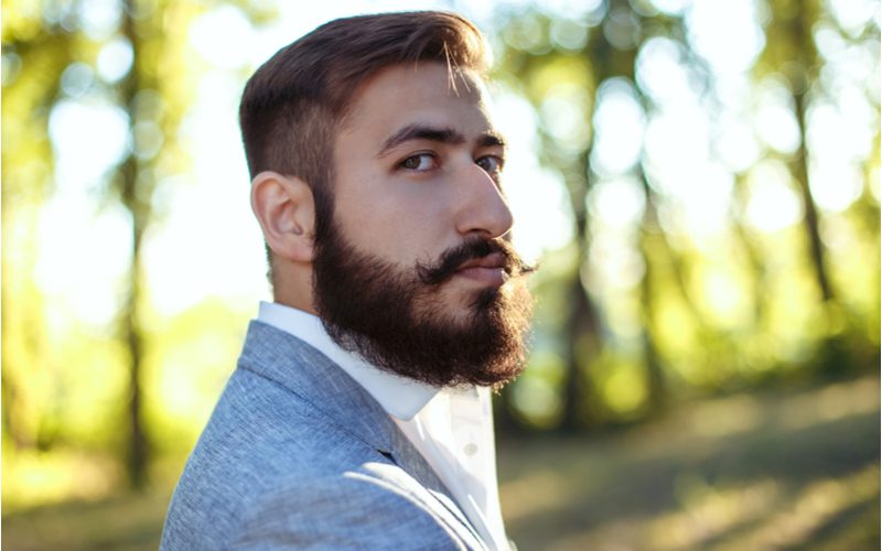 Dapper Comb Over Burst Fade worn by a man in a blue grey blazer with white button up shirt