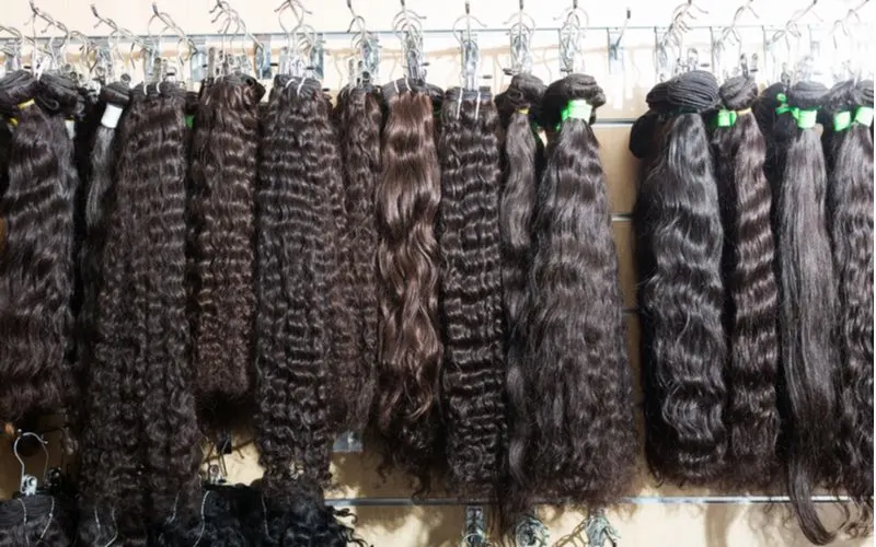 Assortment of virgin hair extensions hanging from a shelf in a braiding studio