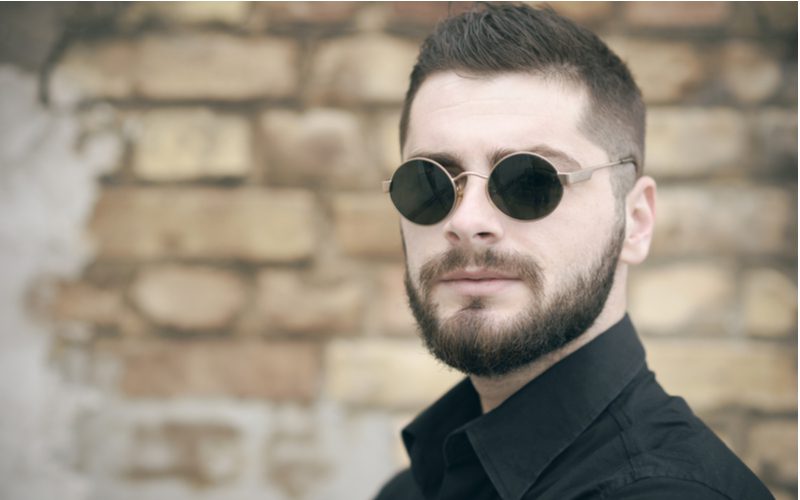Cropped Comb Over Mid Fade worn by a man in dark round modern sunglasses and a black button up shirt