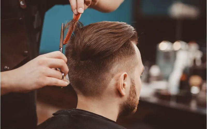 For a piece on popular haircuts for men, a guy with a long, slicked-back pompadour getting his top hair trimmed