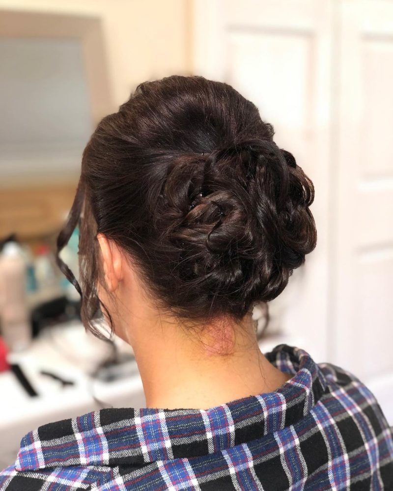 Wedding guest hairstyle titled Neat Bun on a woman in a plaid shirt