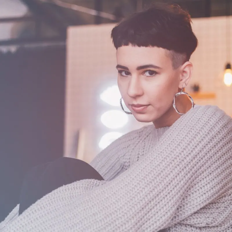 Micro Mushroom Undercut Haircut on a gal with shaved sides in a grey sweater