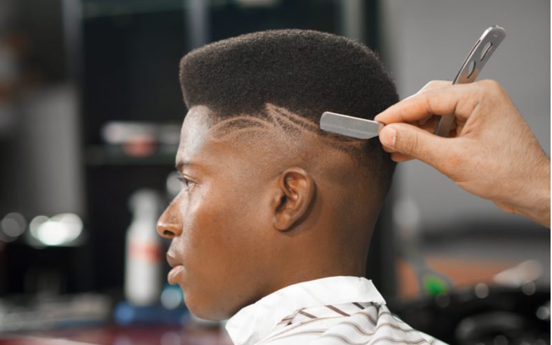 High Top Bald Fade on a black man getting a shaved design into the back of his hair