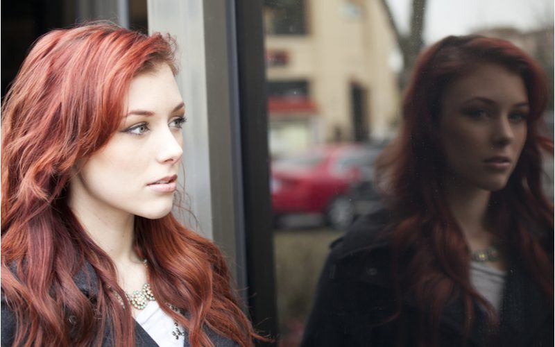 Strawberry Pink Auburn hair on a woman looking in a window