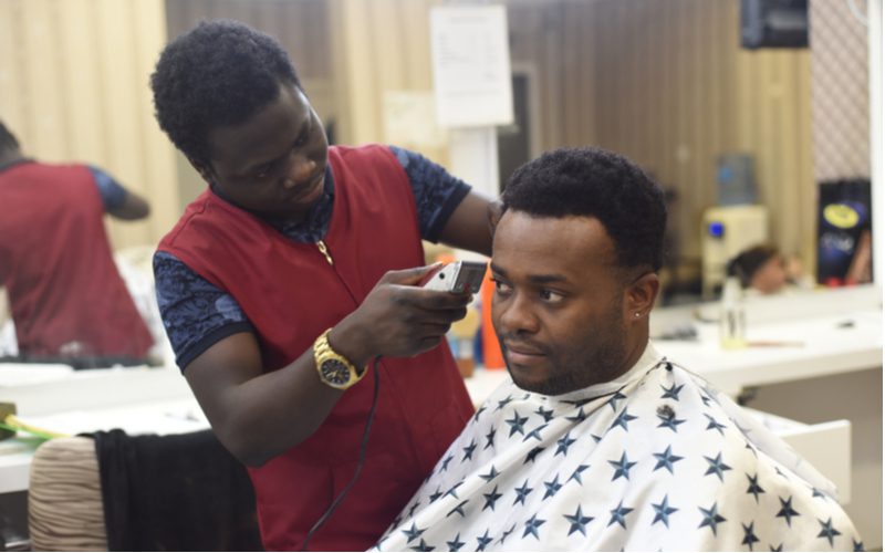 Black man in a barber's chair getting a haircut for a piece on black male hairstyles