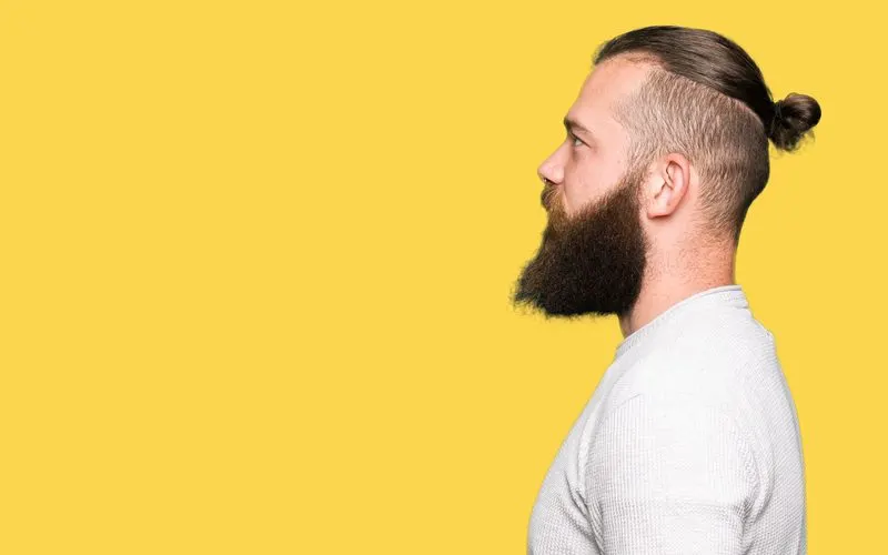 High Undercut With Midi Man Bun haircut on a guy in a white shirt in a yellow room in a side profile image