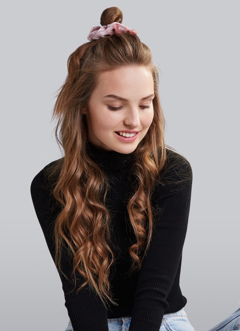 Curly With Half-Up Top Knot as an easy hairstyle on a woman in a black long-sleeve turtleneck
