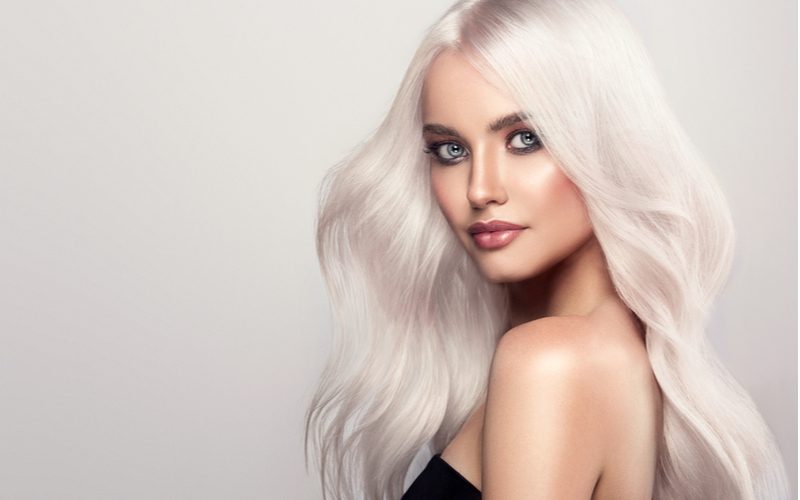 How-to guide on how to get white hair featuring a woman with piercing blue eyes with white hair wearing a black strapless dress