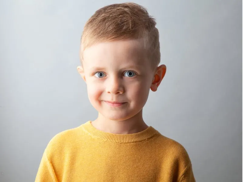 Side-Swept Crew Cut on a little boy in an orange sweater for a piece on little boy haircuts