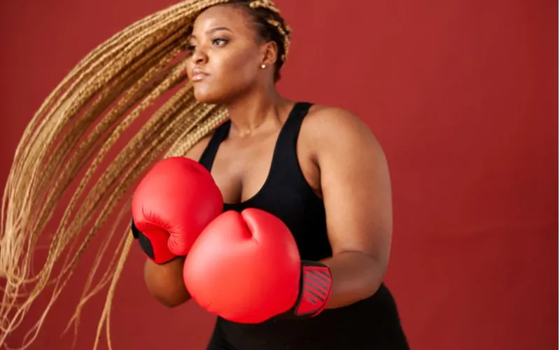Woman rocking goddess locks wearing boxing gloves and a black workout tank