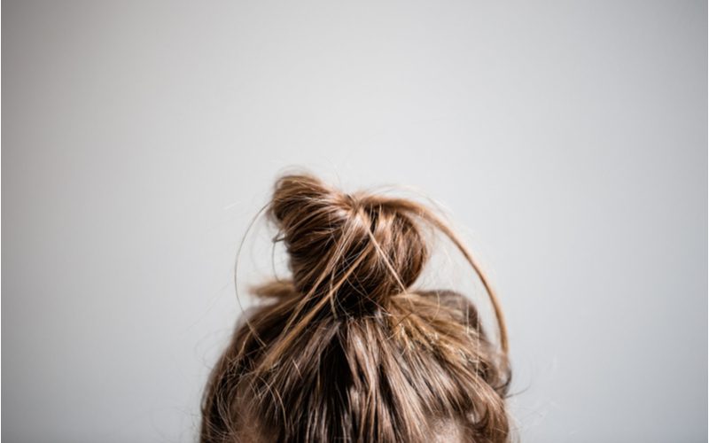 Girl using a bun to get heatless curls featuring a close-up of just the top of her head on which rests a bun