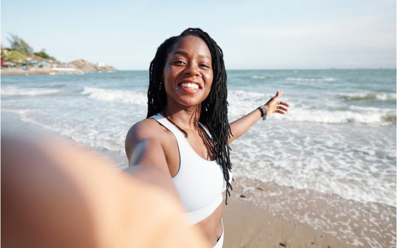 Loose Wavy Sisterlocks on a gal in a white swimsuit on a beach