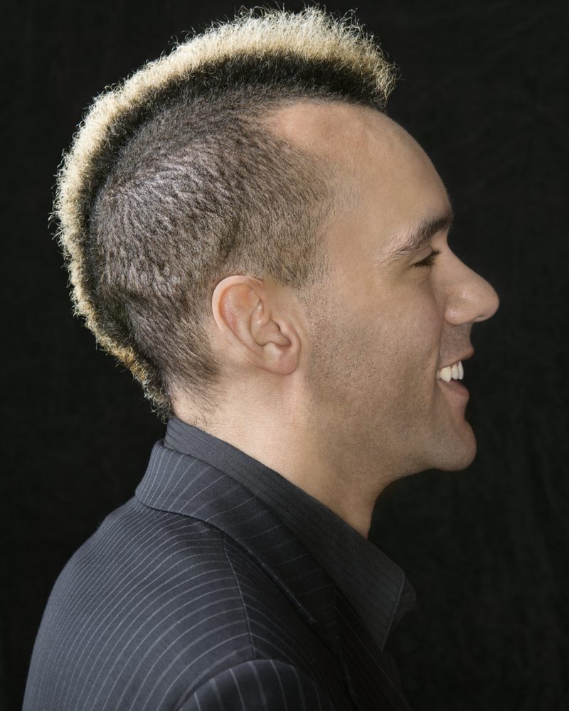 Half and Half ‘Hawk Haircut with bleached tips and a mid fade on the sides in a side profile image