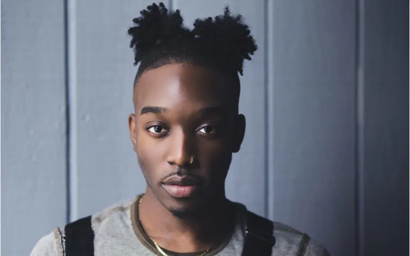 Double Puffs, a unique and somewhat strange black male hairstyle, on a guy wearing a backpack and grey Henley shirt