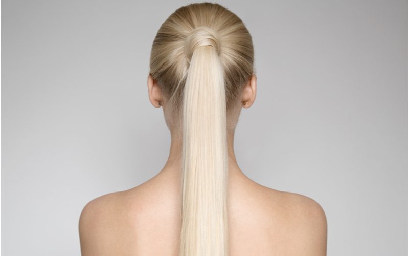 Woman without a shirt looking away from the camera with an Elegant Wrapped Ponytail that hangs down to her mid-back
