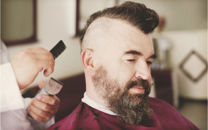 Wedge Mohawk haircut for receding hairlines getting cut on a man in a barber chair