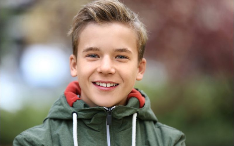 Little boy with a Casual Long-Top Taper (a featured little boy's haircut) wearing a green canvas hooded jacket