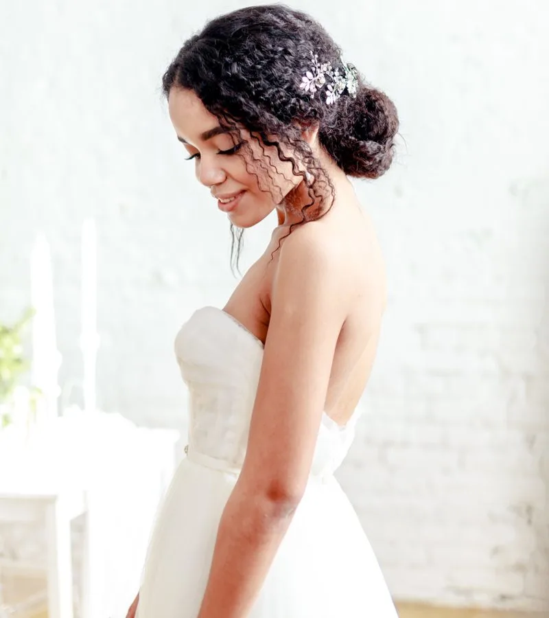 African American bride wearing a Natural Chignon With Loose Pieces and Floral Accent hairstyle