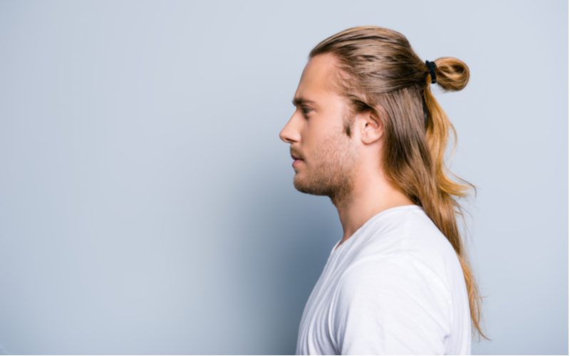 Half-Up Low Pull-Through Bun on a man in a white shirt in a blue room in a side profile image