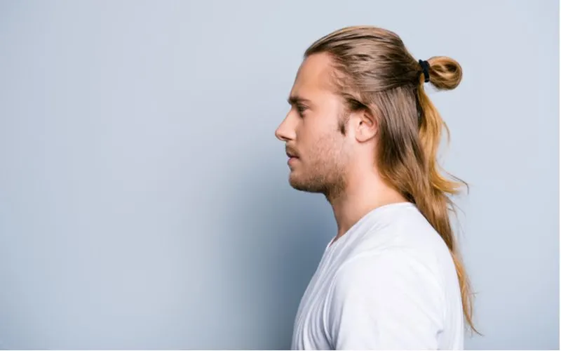 Half-Up Low Pull-Through Bun on a man in a white shirt in a blue room in a side profile image