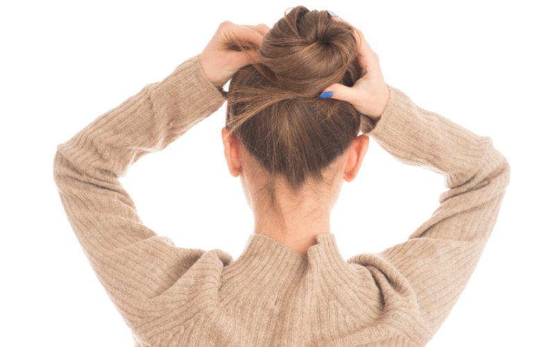 High Twisted Bun being held by a girl with both her hands above her head for a piece on easy hairstyles