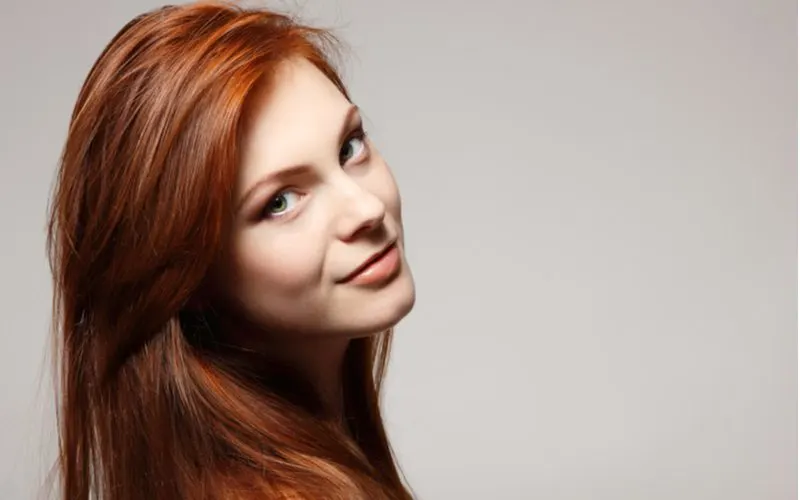 Lady with auburn hair looking right and grinning while tilting her head to the right