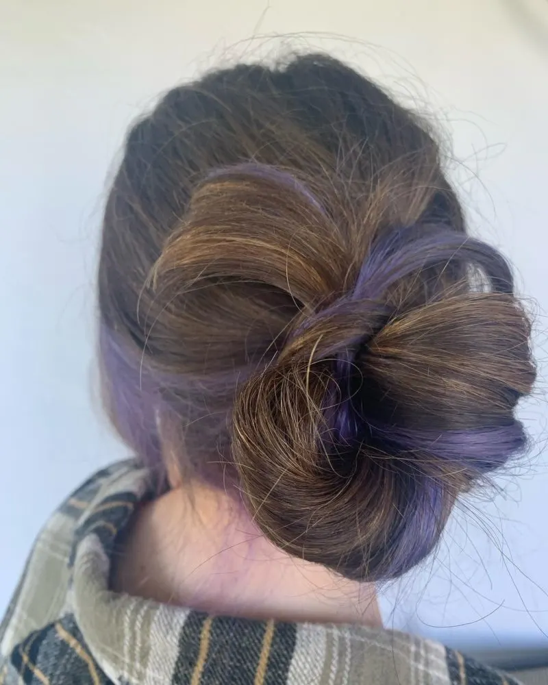 Black and purple hairstyle with a lilac bun that's hardly noticeable unless you're close up, as shown from the back