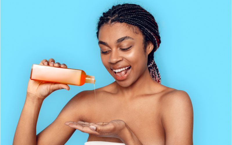 Woman who has scalp sores from tight braids pouring conditioner into her hand to oil the scalp