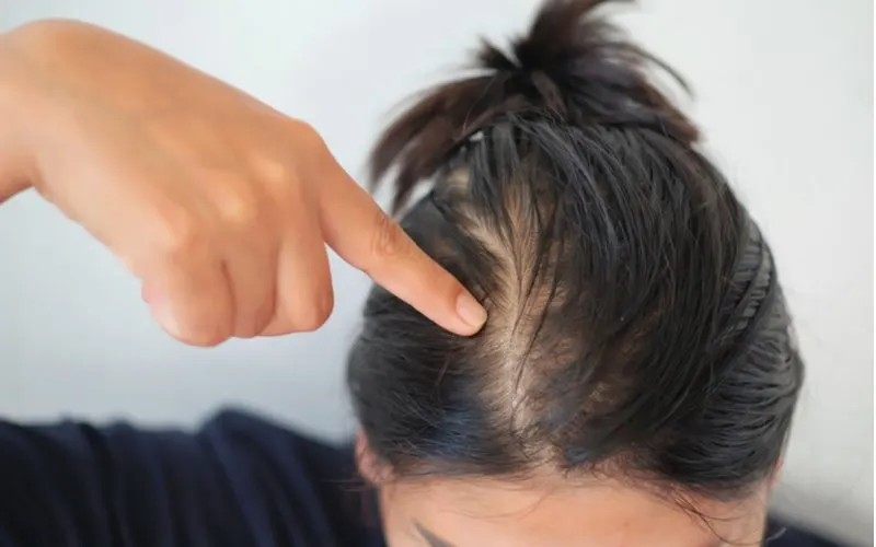 Woman with 1a hair pointing at her scalp