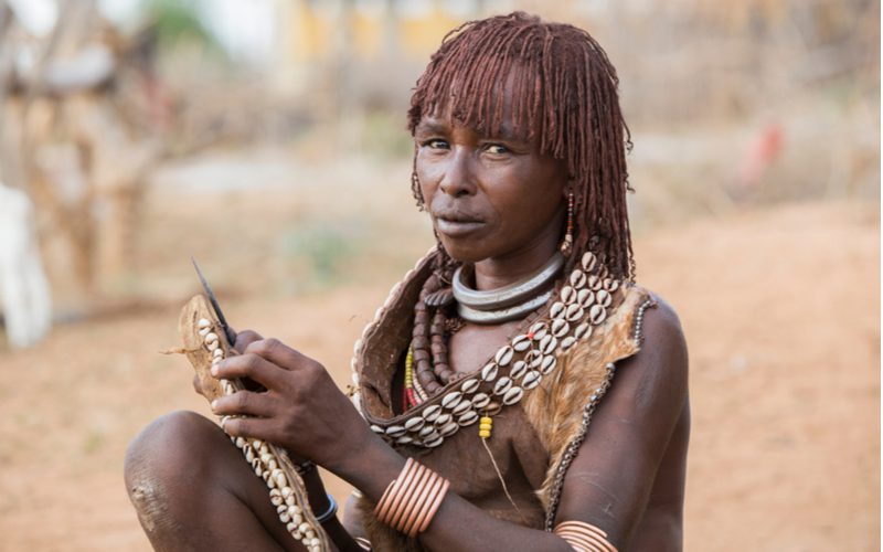 Woman with micro locs pictured in Ethiopia sitting on the ground