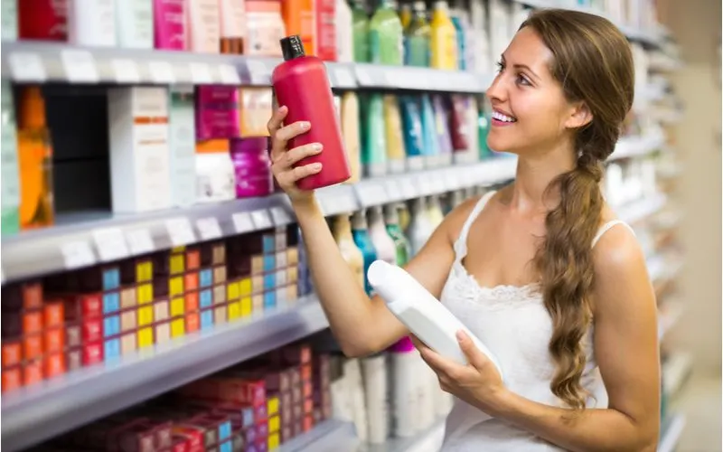 Happy woman smiling while holding the best shampoo for colored hair