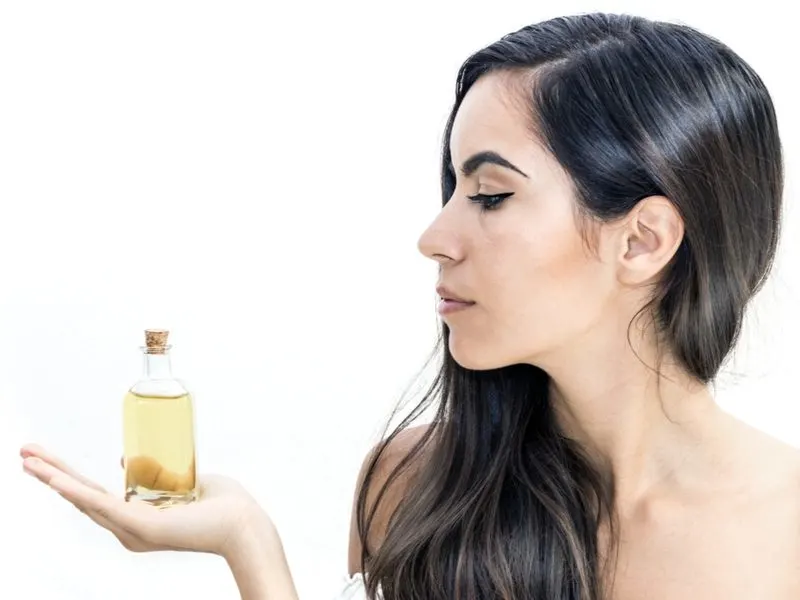 Woman holding a vile of Argan Oil for hair in her hand